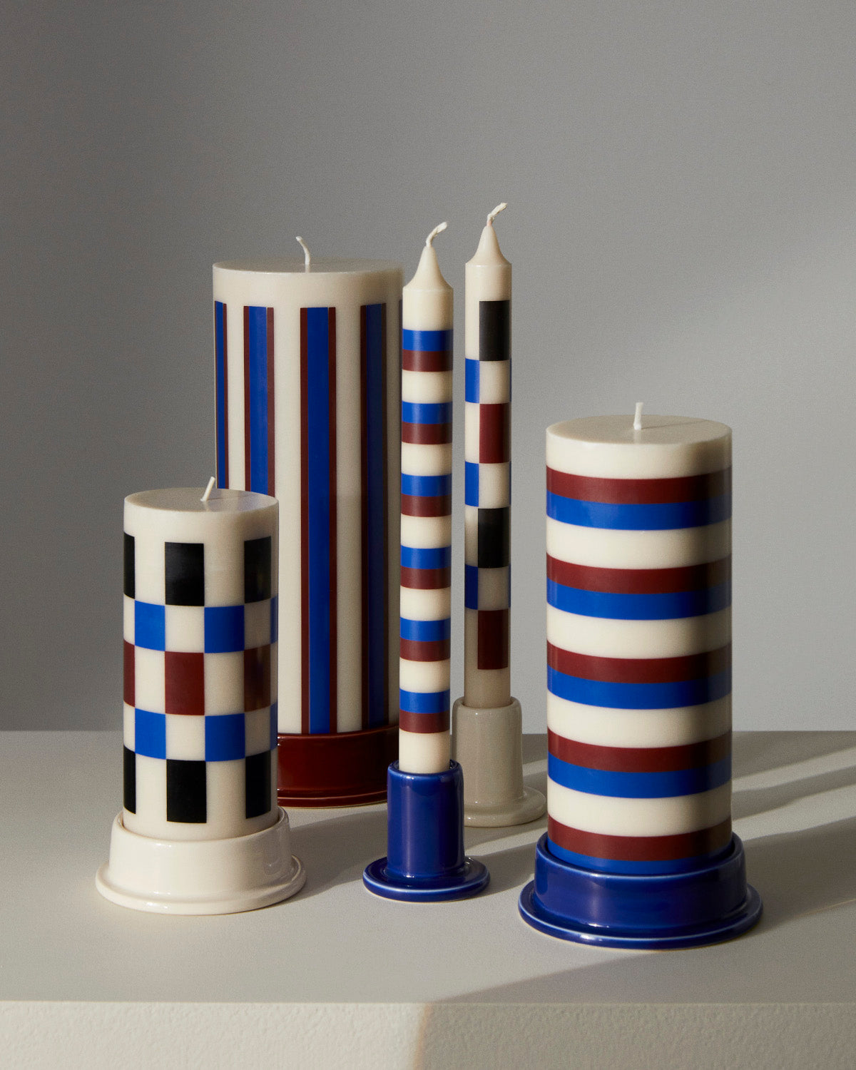 A selection of HAY patterned dinner candles stand in individual coloured holders on a square table