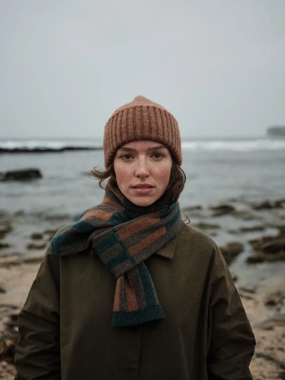 A model wearing a Hilary Grant Small Scarf in Autumn on a beach in Scotland