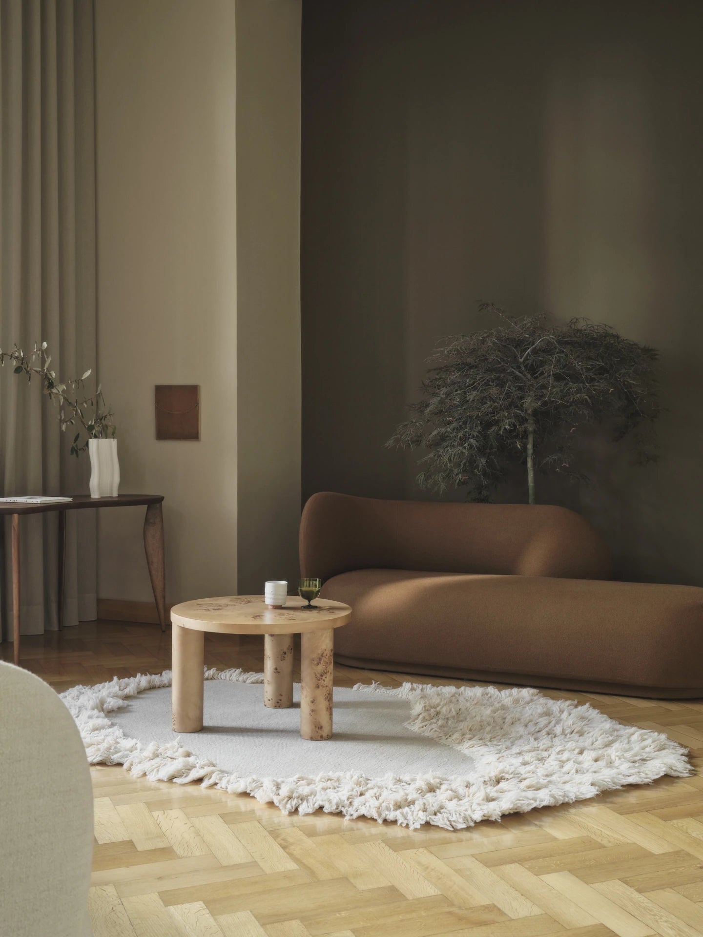 Ferm Living Rico Divan in dark brown in a wooden floored room with dark green walls