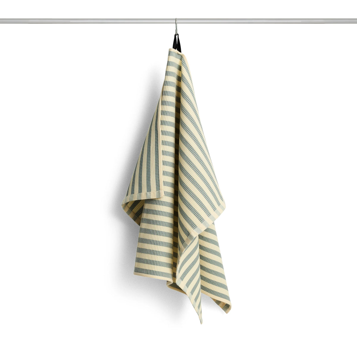 Striped green and yellow HAY Canteen towel hanging on a rack against a white background