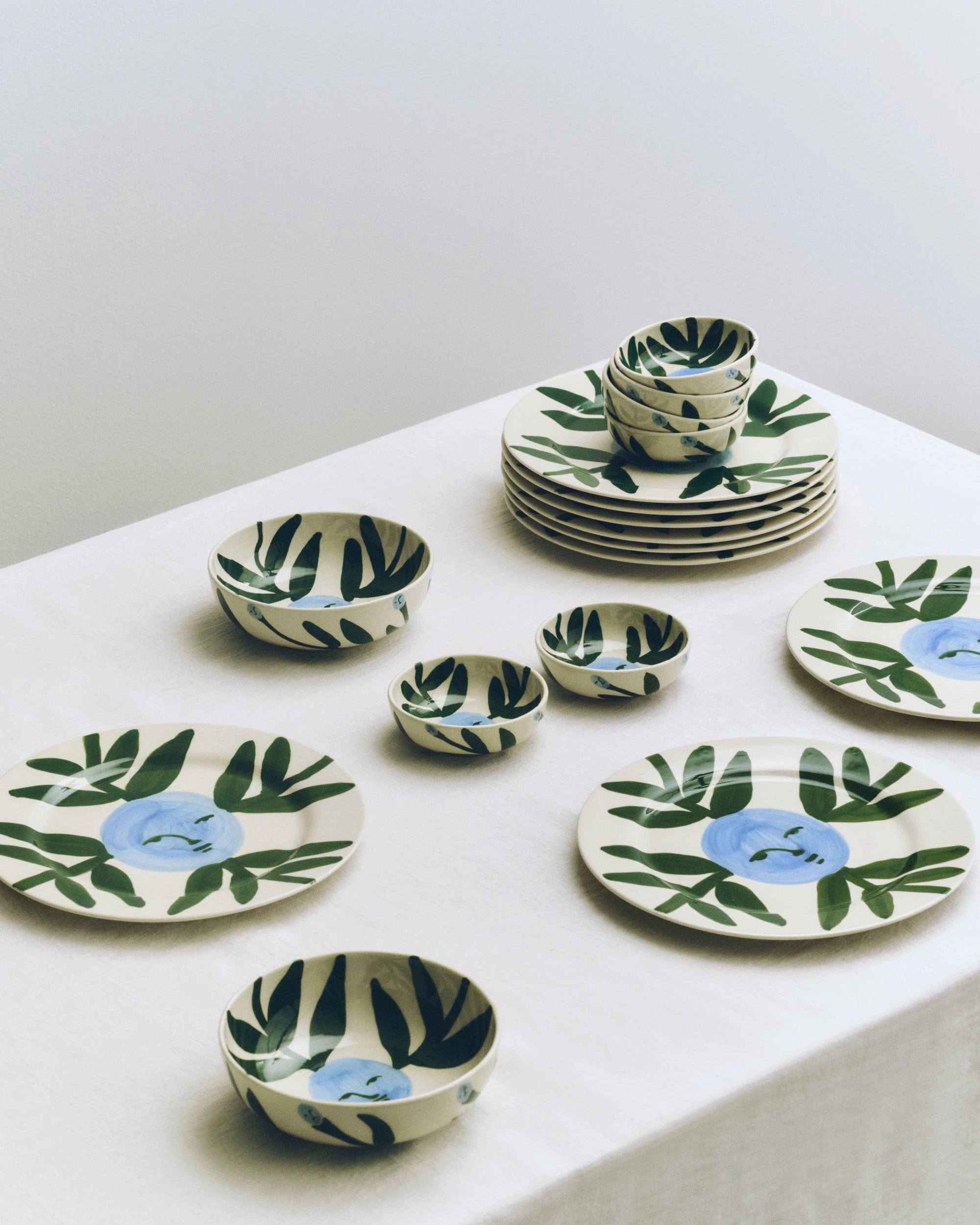 HAY x Emma Kohlmann - La Pittura Moon Face Vine tableware collection in piles on a white tableclothed surface