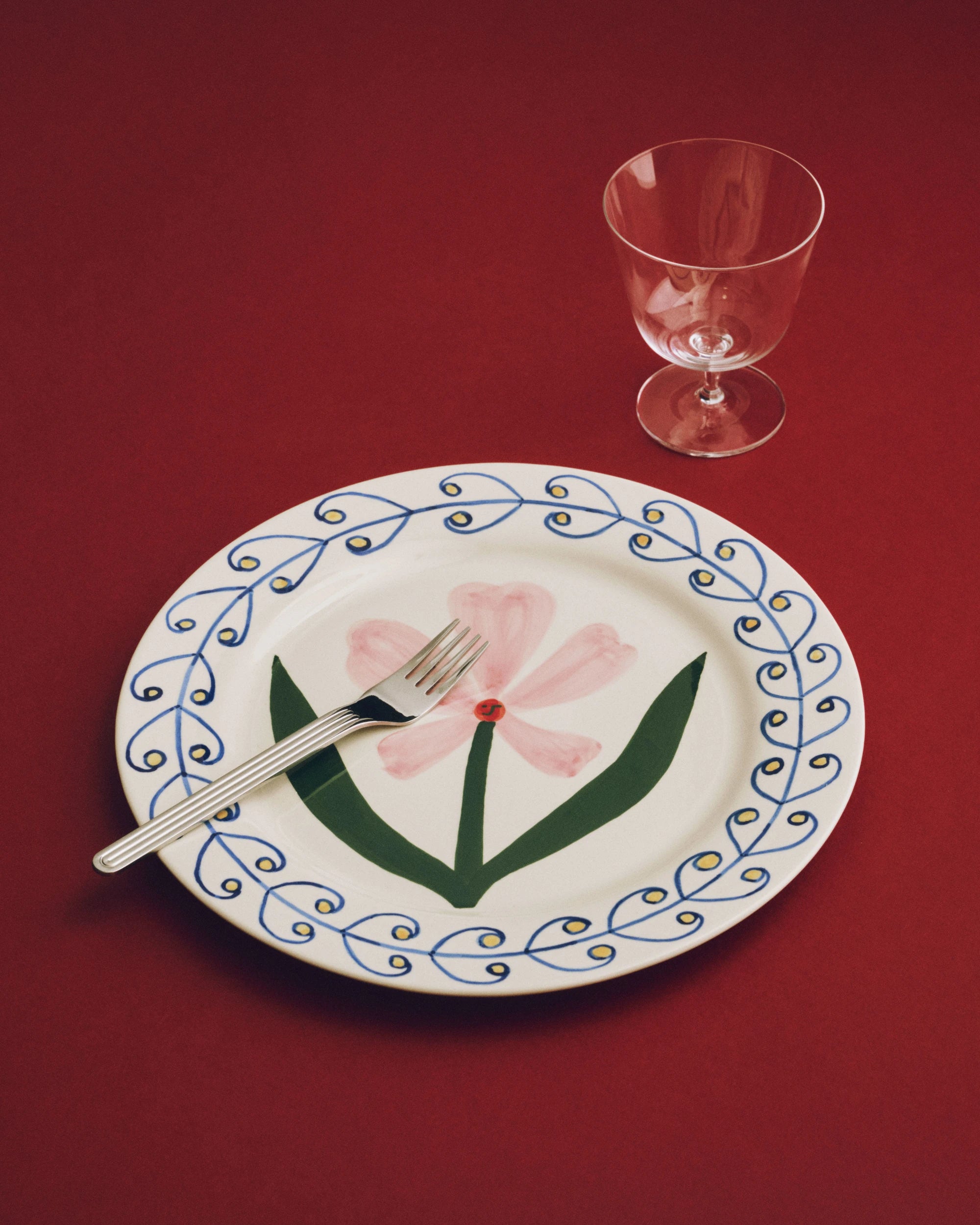 HAY x Emma Kohlmann - La Pittura Ø28.5cm Plate in Antiquity design on a red surface with a fork and glass