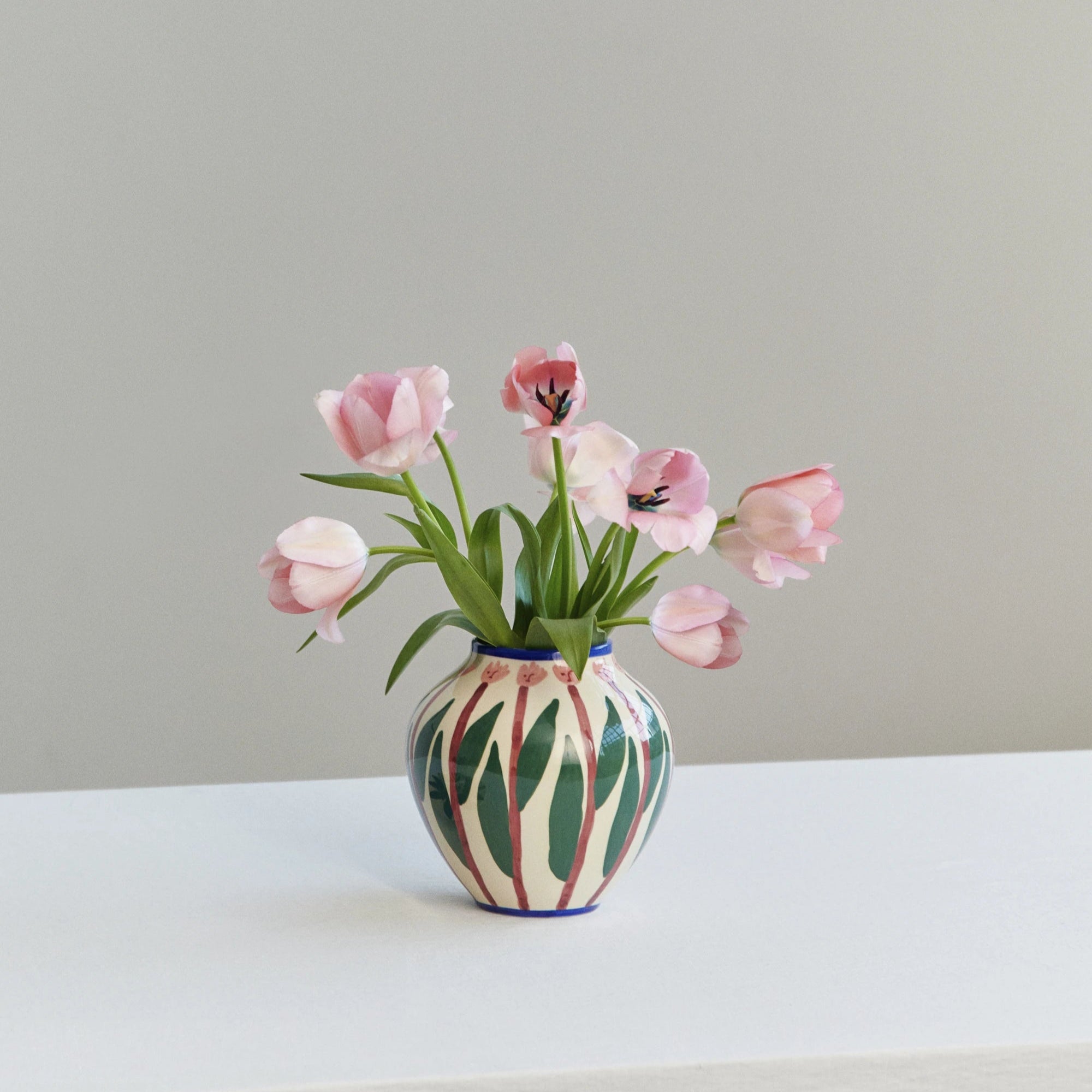 HAY x Emma Kohlmann - La Pittura Vase in Omi design standing on a white surface and filled with pale pink tulips