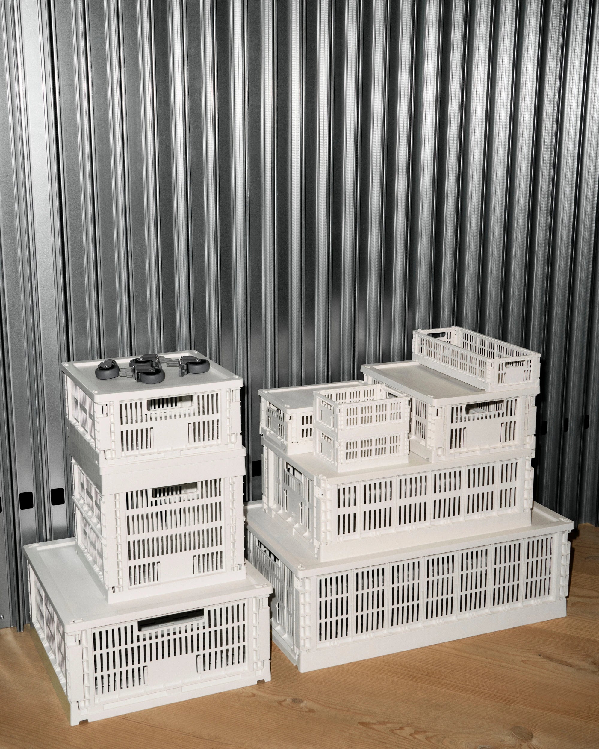 Set of white HAY Colour storage crates stacked against a metallic curtain background