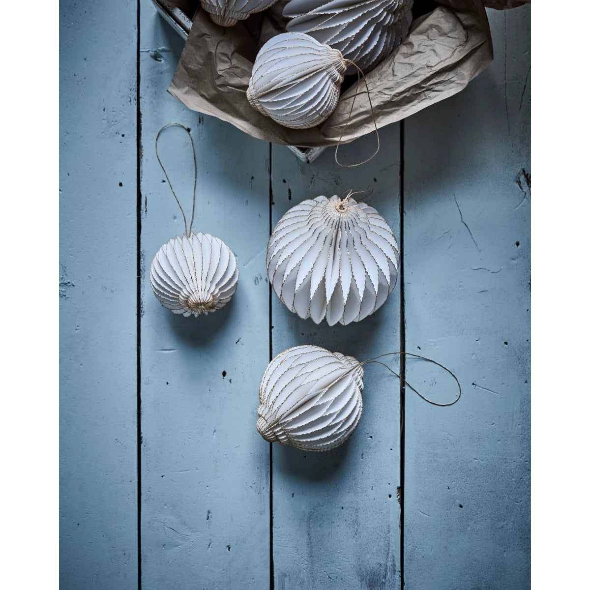 House Doctor Set of 4 'Alsta' Paper Hanging Ornaments with other decorations on a blue wooden background