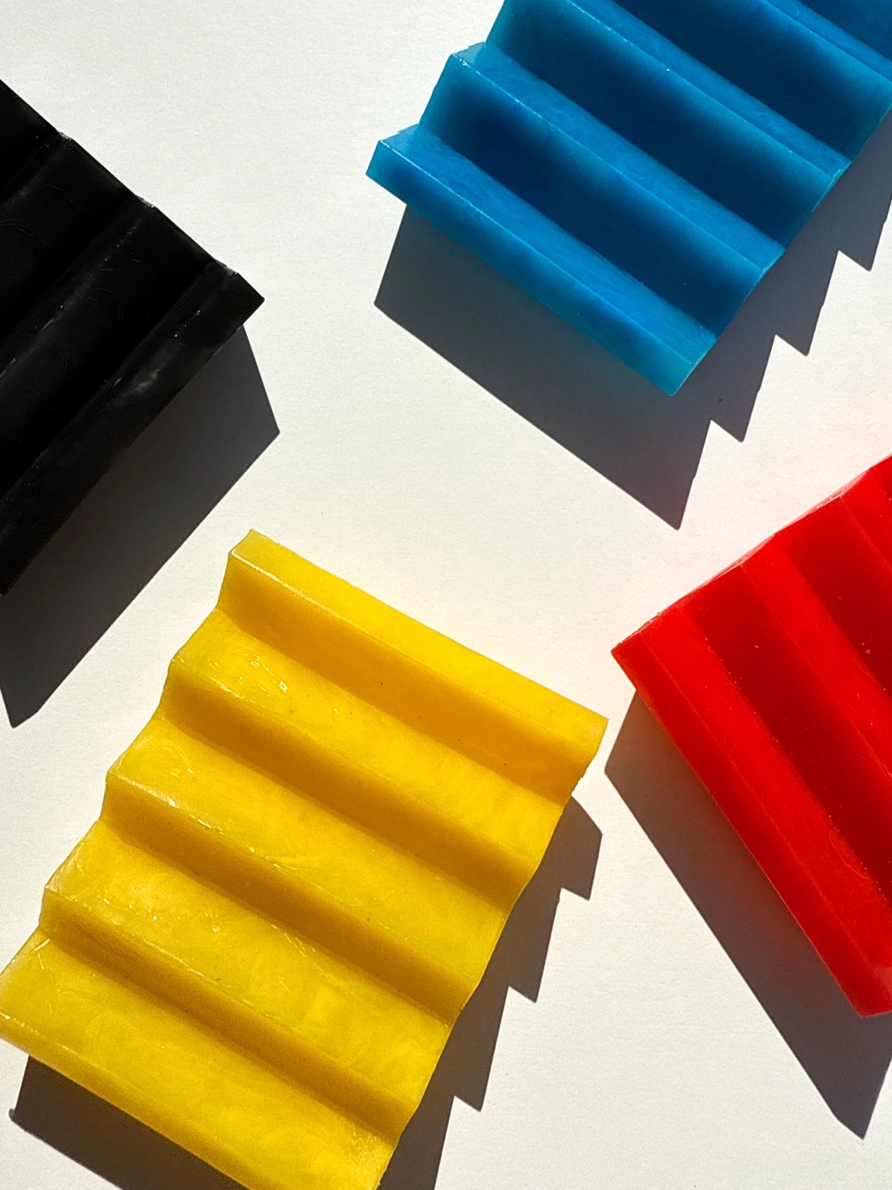 Primary colour zig zag soap dishes on an off white background