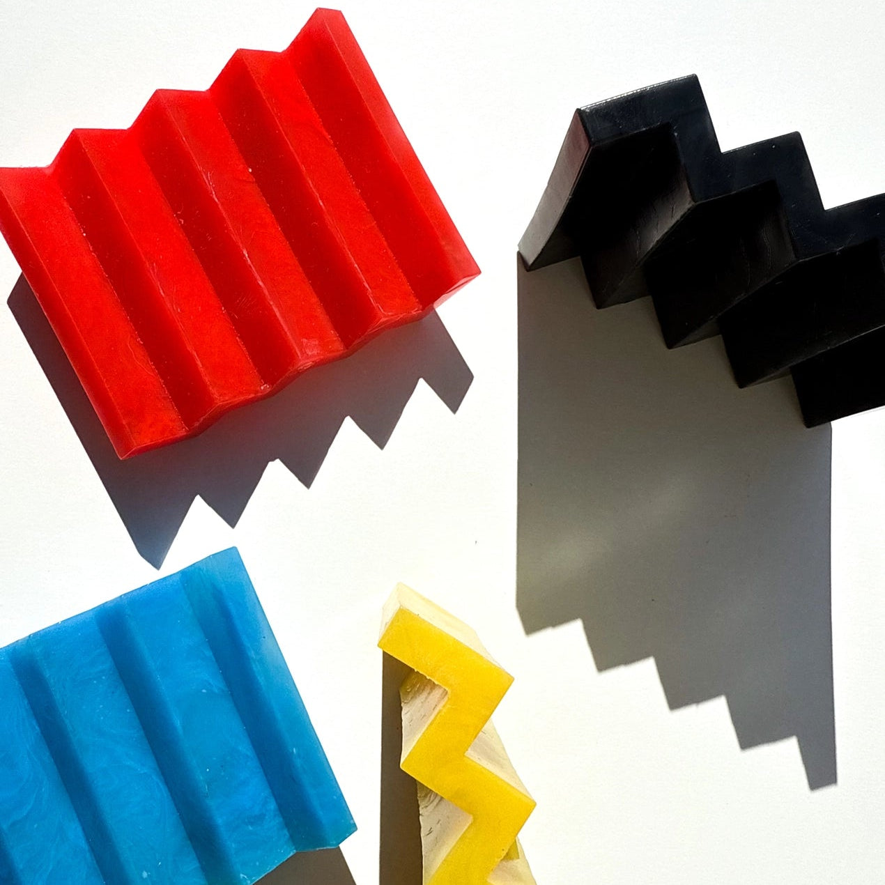 Primary colour zig zag soap dishes on an off white background