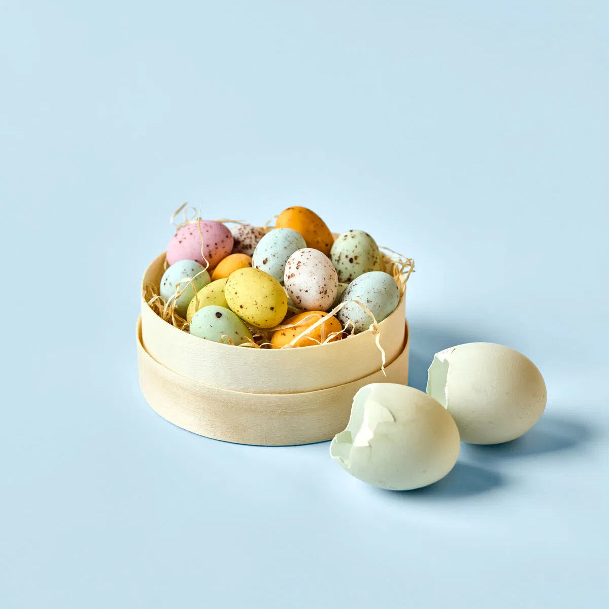 Colorful Easter eggs in a wooden basket on a light blue background