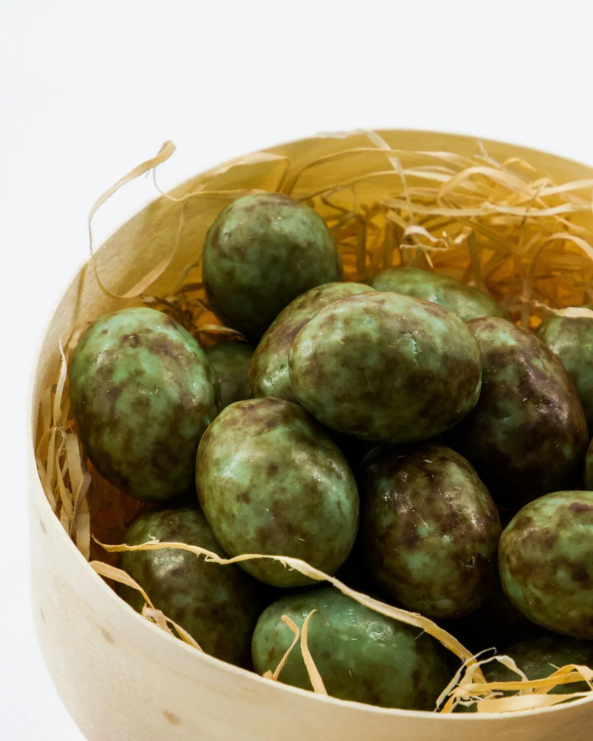 Basket filled with green speckled eggs on a white background