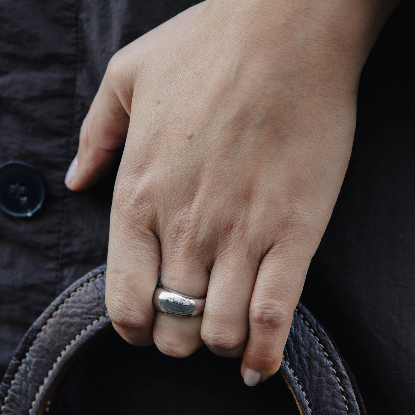 Dome Ring with Water Resistant Silver Plating by Nordic Muse being worn by a hand holding a leather bag strap
