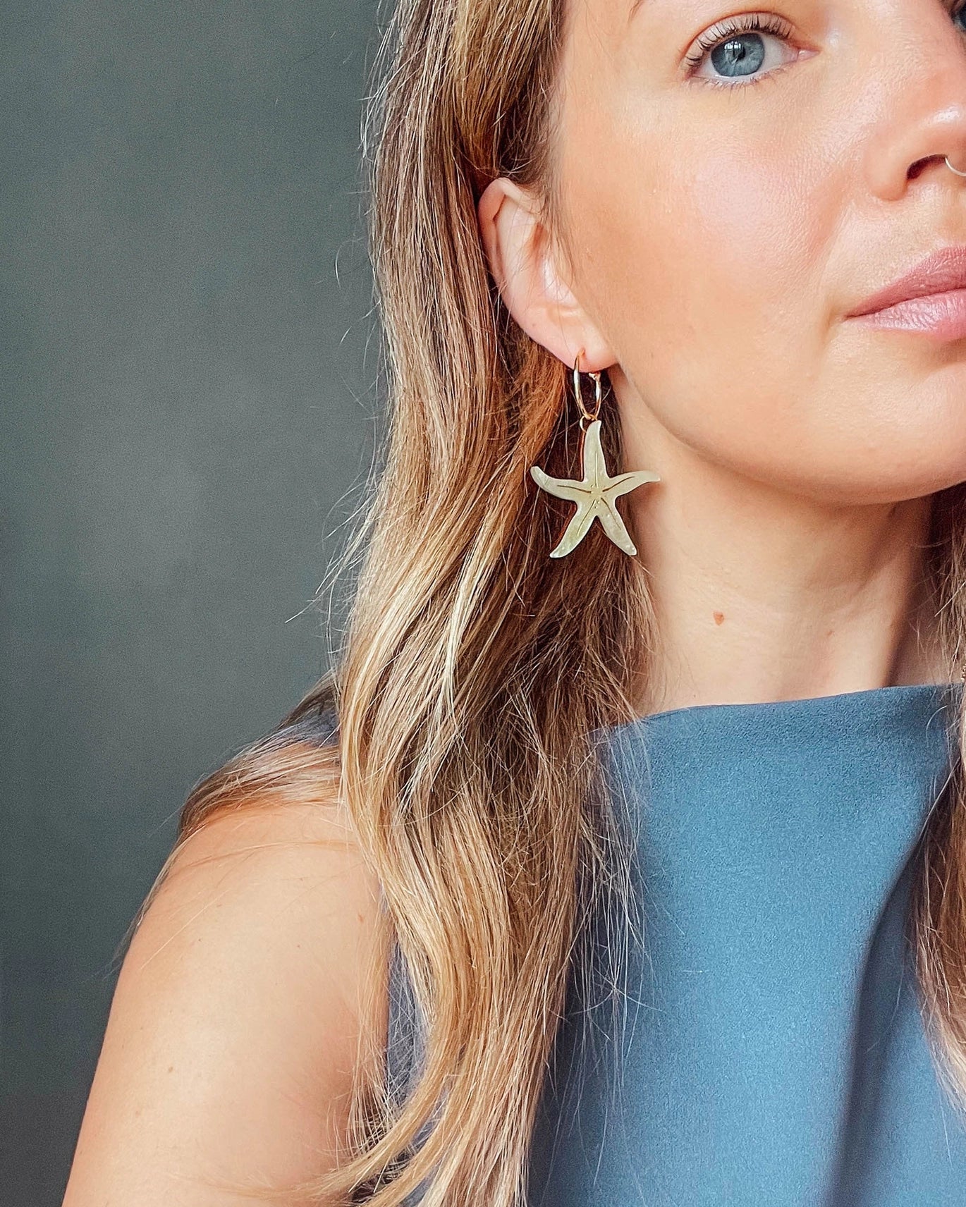 Pepper You Acrylic & Wood Pearly Statement Starfish Hoop Earrings in Lemon Yellow being worn by a white woman with blonde hair wearing a blue top