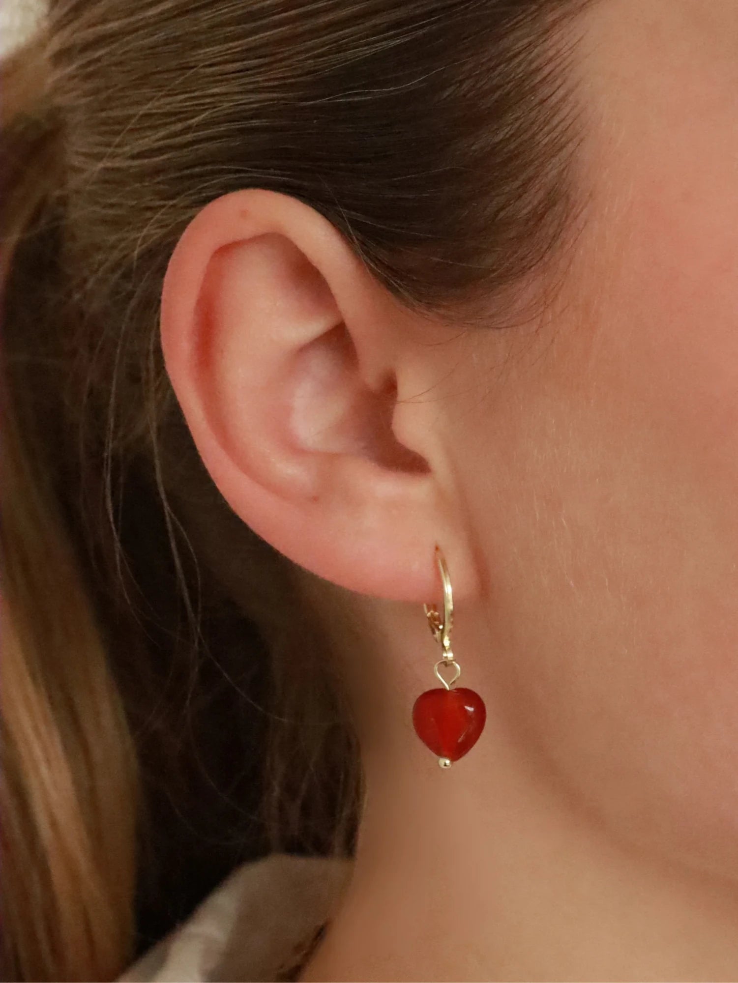 Woman wearing Soï Copenhagen Alma Red Jade heart earrings in 18k gold