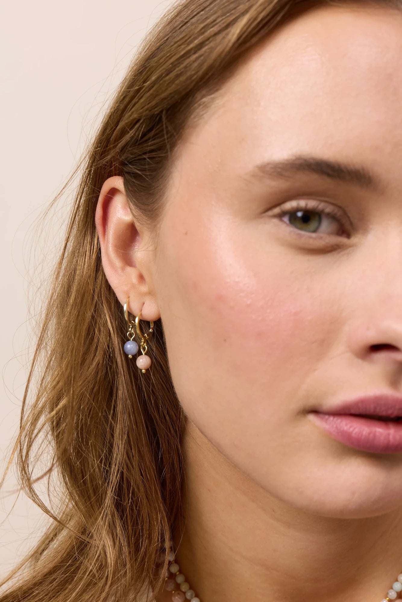 Model wearing Soï Copenhagen Ava huggie hoop earrings in 18k gold with a Sunstone stone