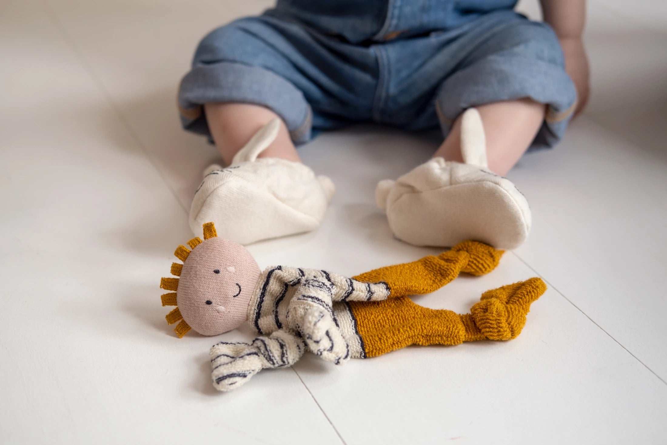 Citrus Buddy Comforter Cuddle Cloth by Sophie Home on a white floor next to a baby