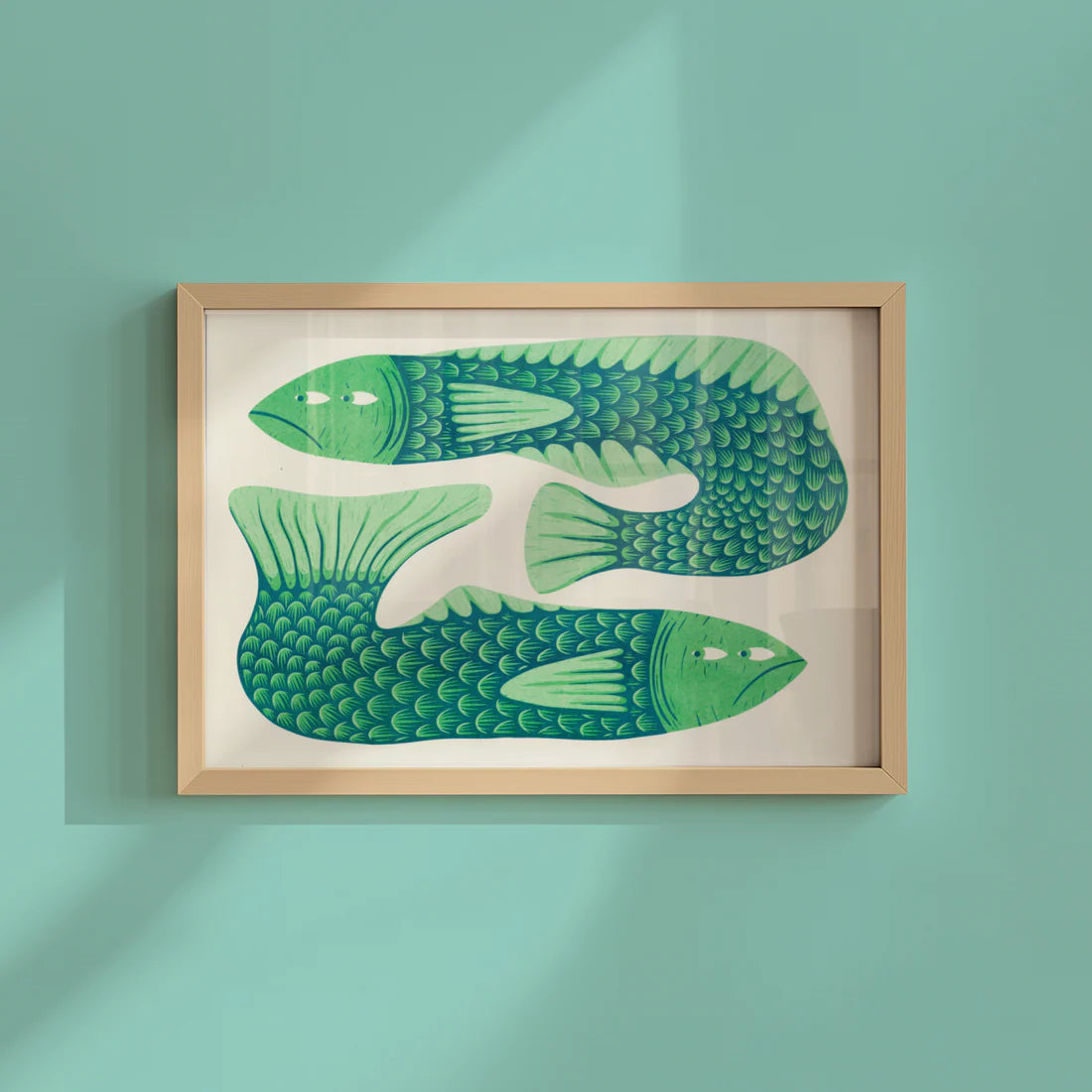 Framed artwork of green fish on a light blue wall