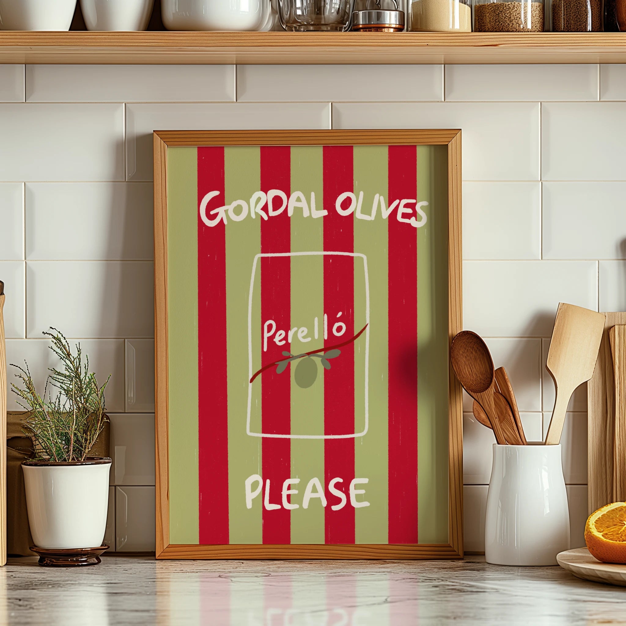 Tecari Designs 'Gordal Olives Please' A3 Unframed Print in a frame on a kitchen worktop next to wooden utensils