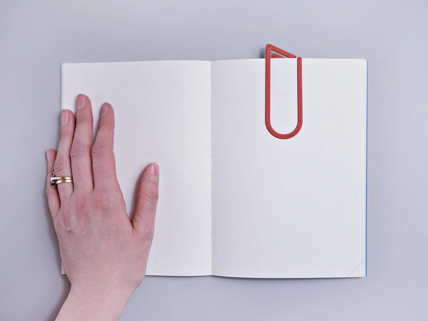 The Completist 3D Printed Modern Bookmark slotted into a book with a human hand for size reference