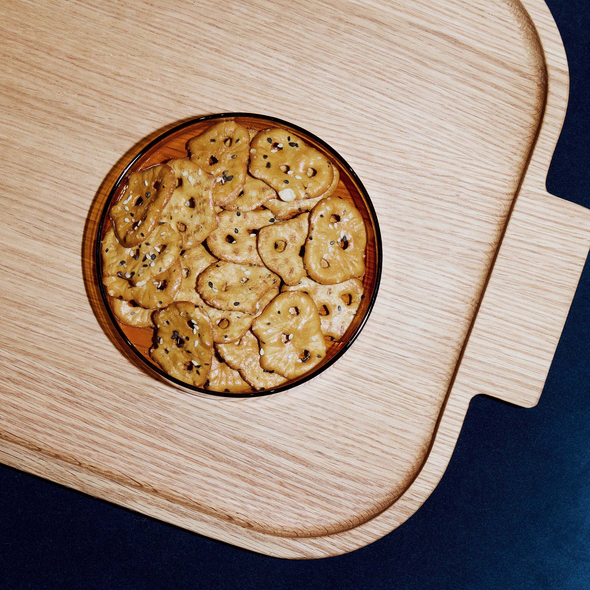 Round glass bowl with crackers on a wooden surface.