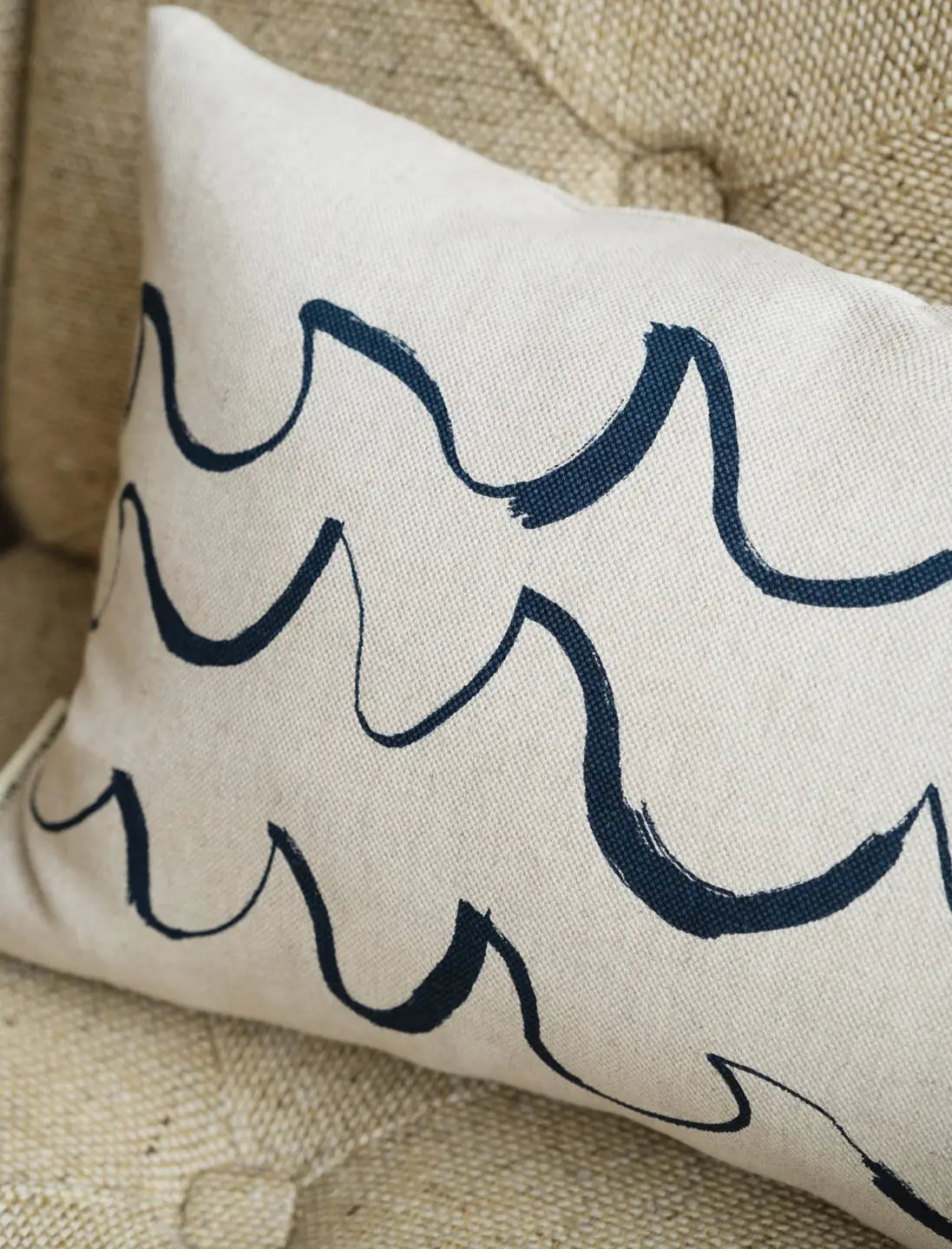 A long cushion in natural linen with a minimal blue wave shaped brush stroke motif from Fine Little Day