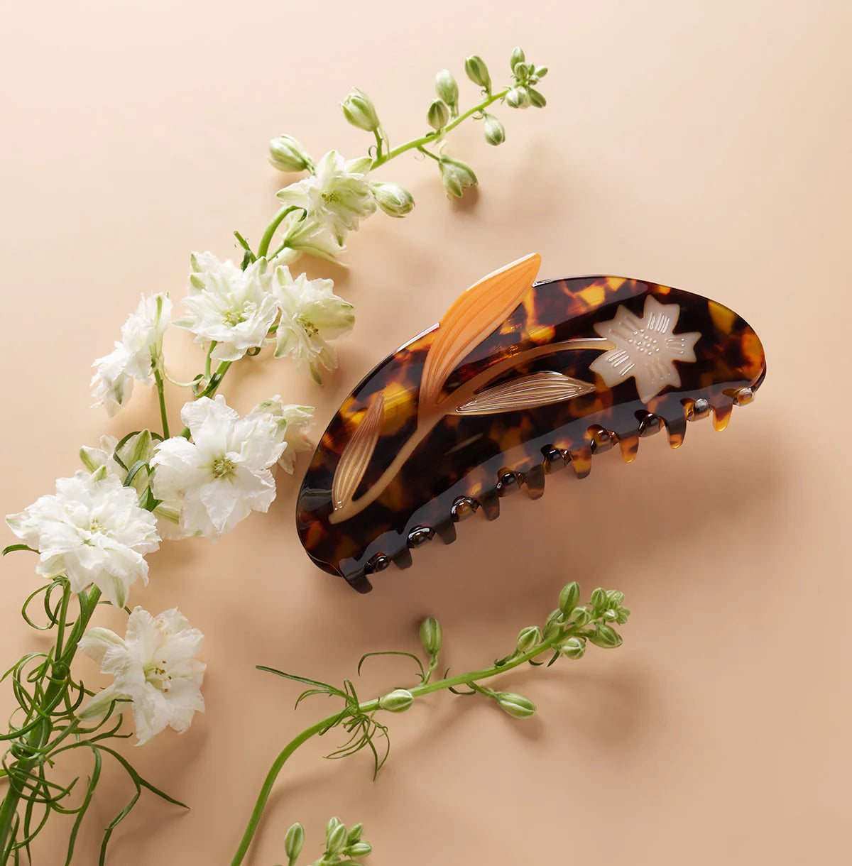 Tortoiseshell hair clip with floral design on a beige background