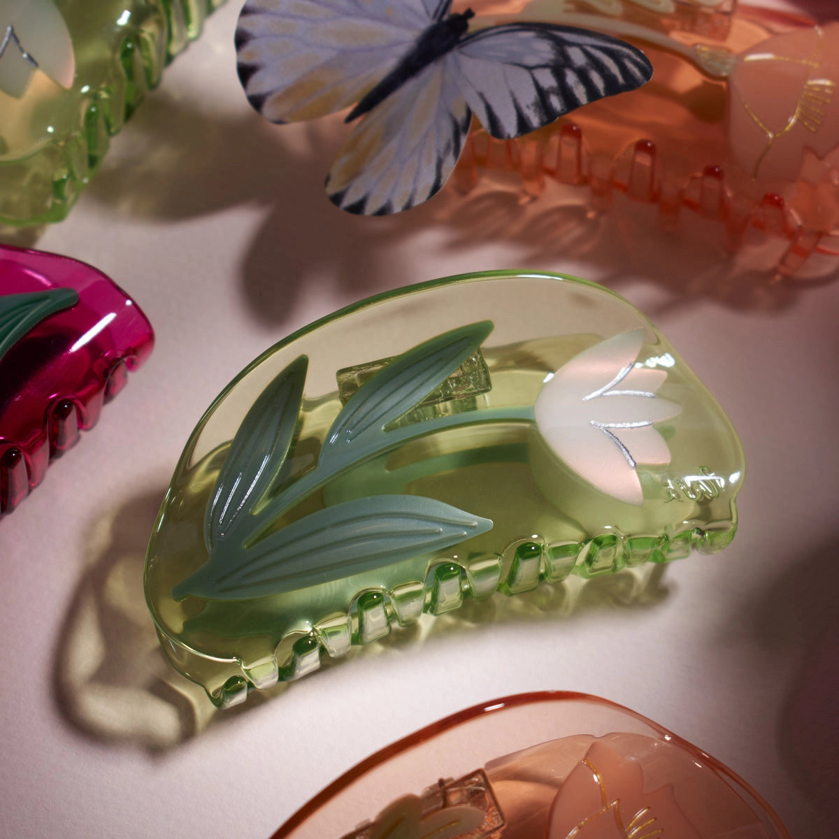 Colorful hair clips with floral designs on a light pink background