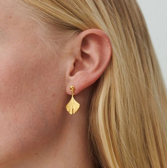 Biloba Earrings in Gold-Plated Silver by Pernille Corydon being modelled by a white woman with blonde hair
