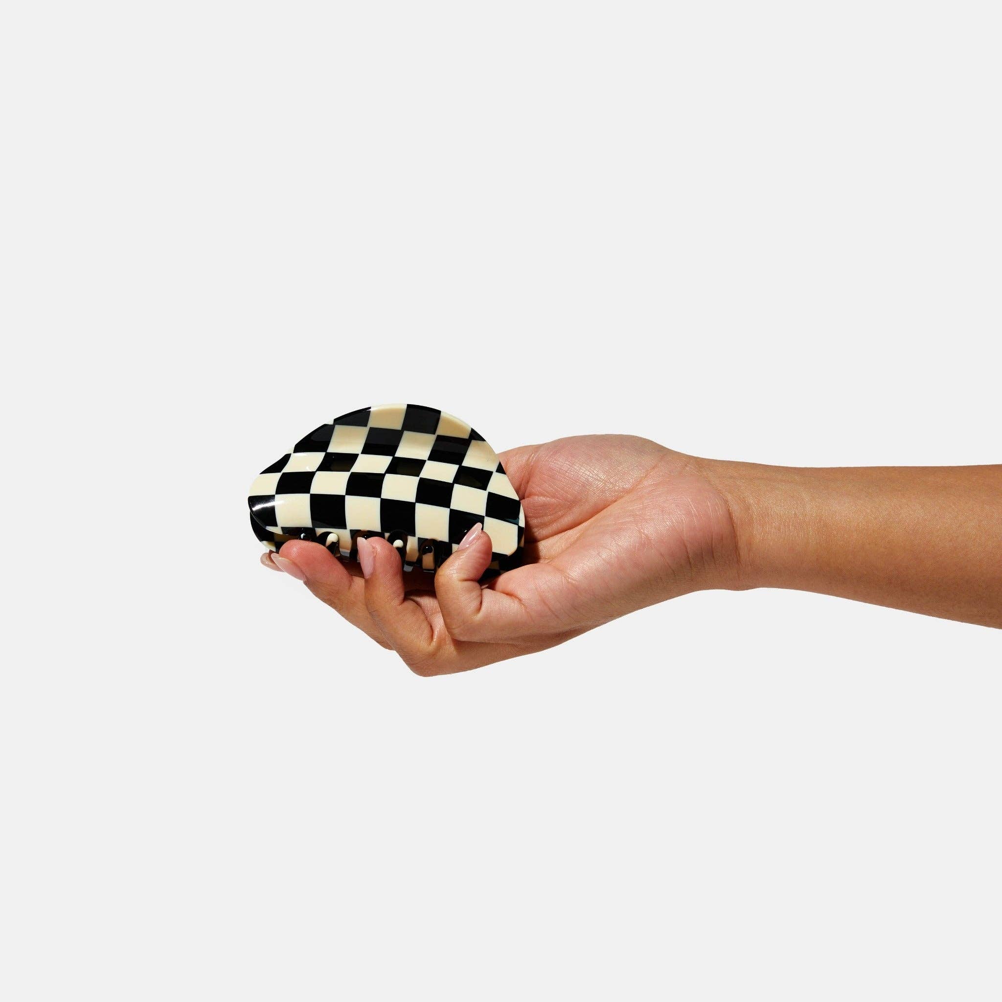 CHUNKS Checker Hair Claw in black and white being held by a models hand
