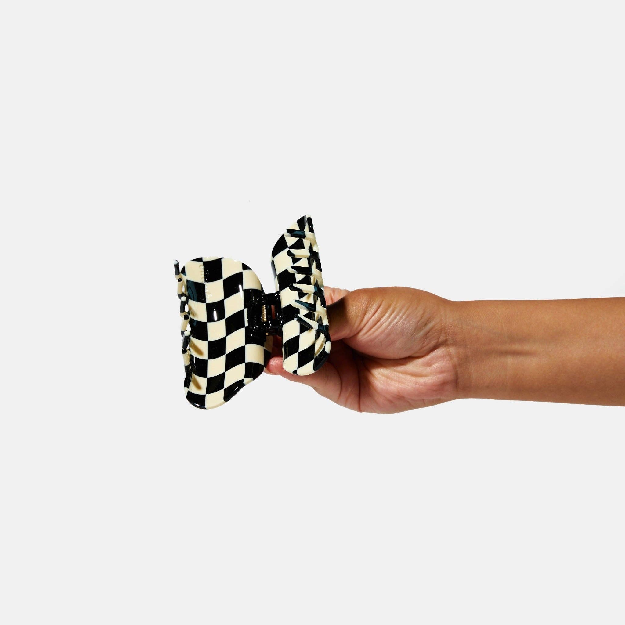 CHUNKS Checker Hair Claw in black and white being held open by a models hand