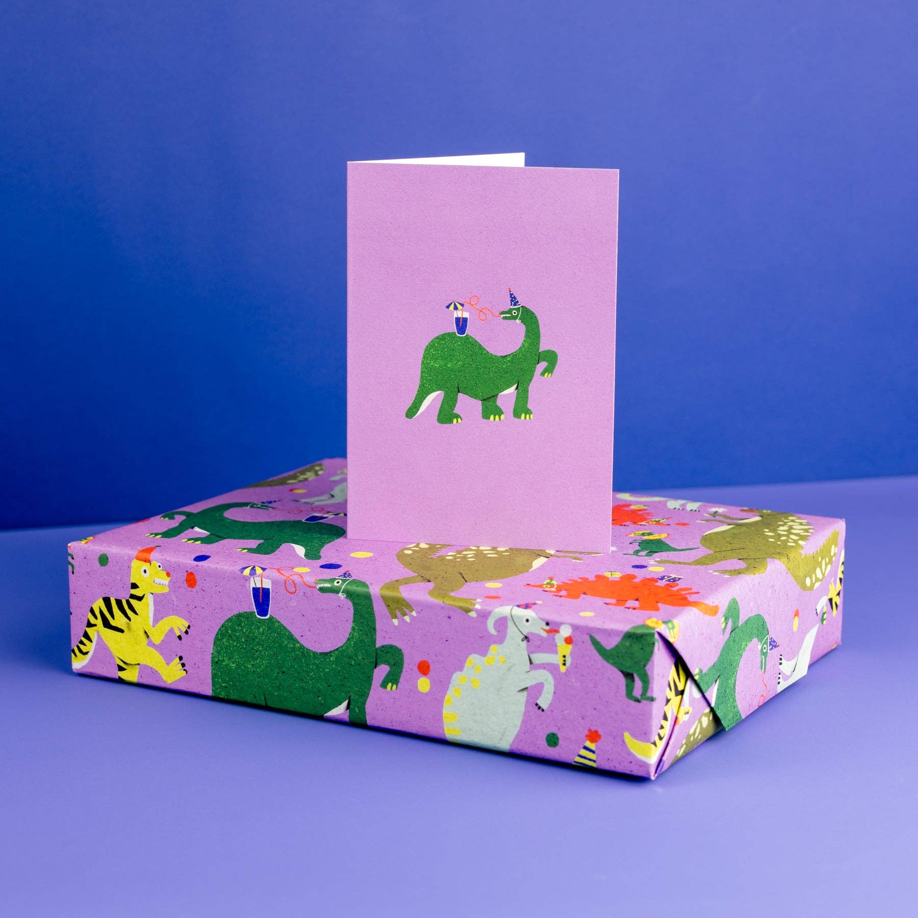 Purple box with dinosaur design and matching card on a blue background
