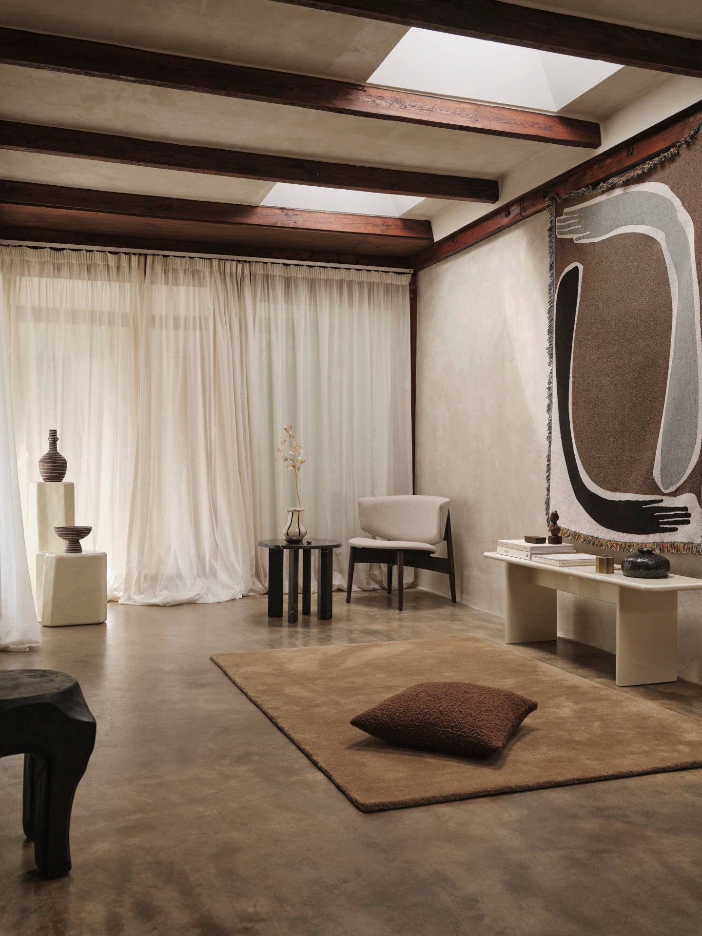 a ferm Living designed livingroom with furniture and a brown rug, with the Pose tapestry blanket hanging on the wall