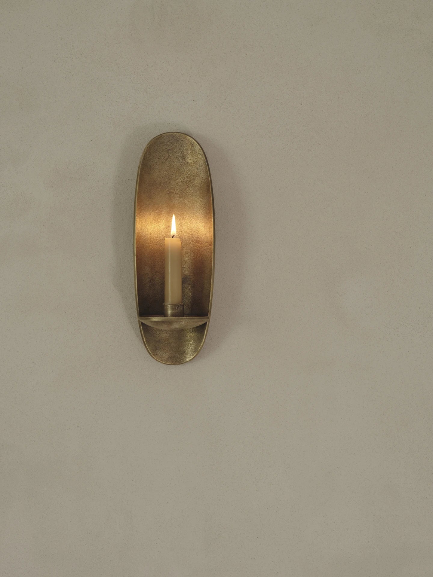Ferm Living Agapé Wall Candle Holder Sconce in Rustic Brass Finish with lit candle