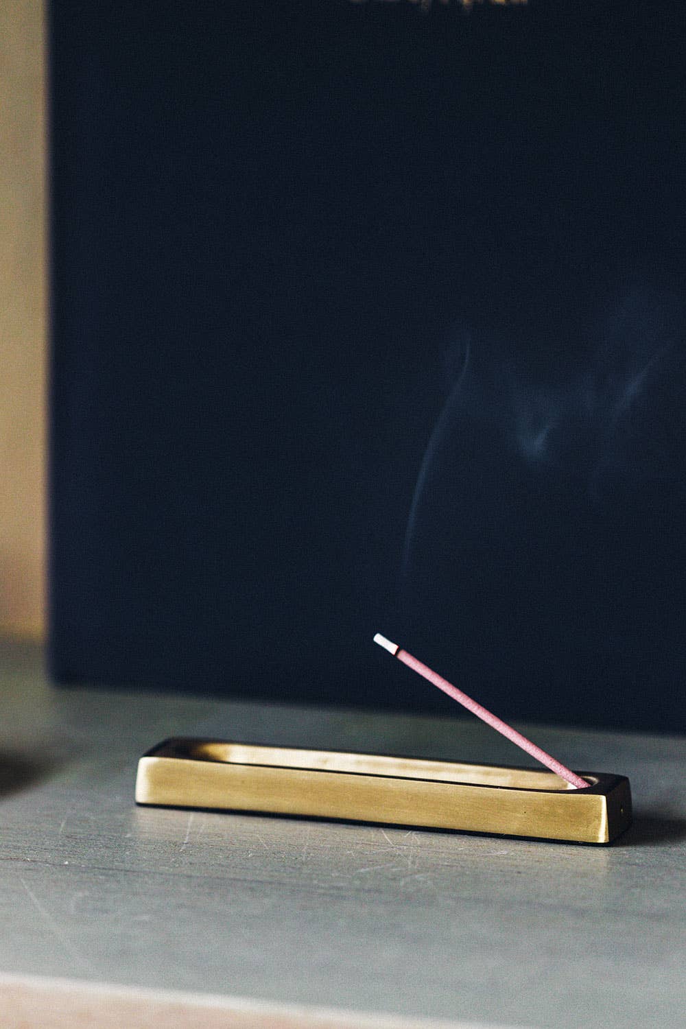 Incense stick burning on a brass incense holder with a dark background
