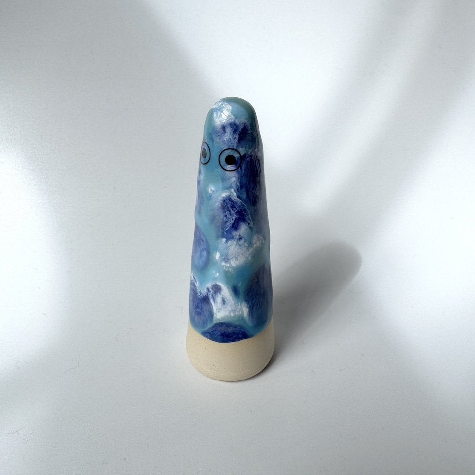 Joey Studio Arhoj ghost, featuring a marbled blue and white glaze with dark blue eyes and a natural beige clay base, set against a plain white background.