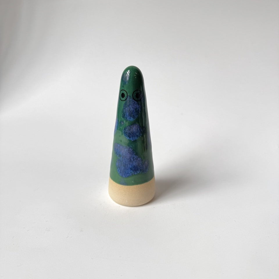 Levi Studio Arhoj ghost with a green and blue speckled body and a natural beige wooden base, standing on a white studio background.