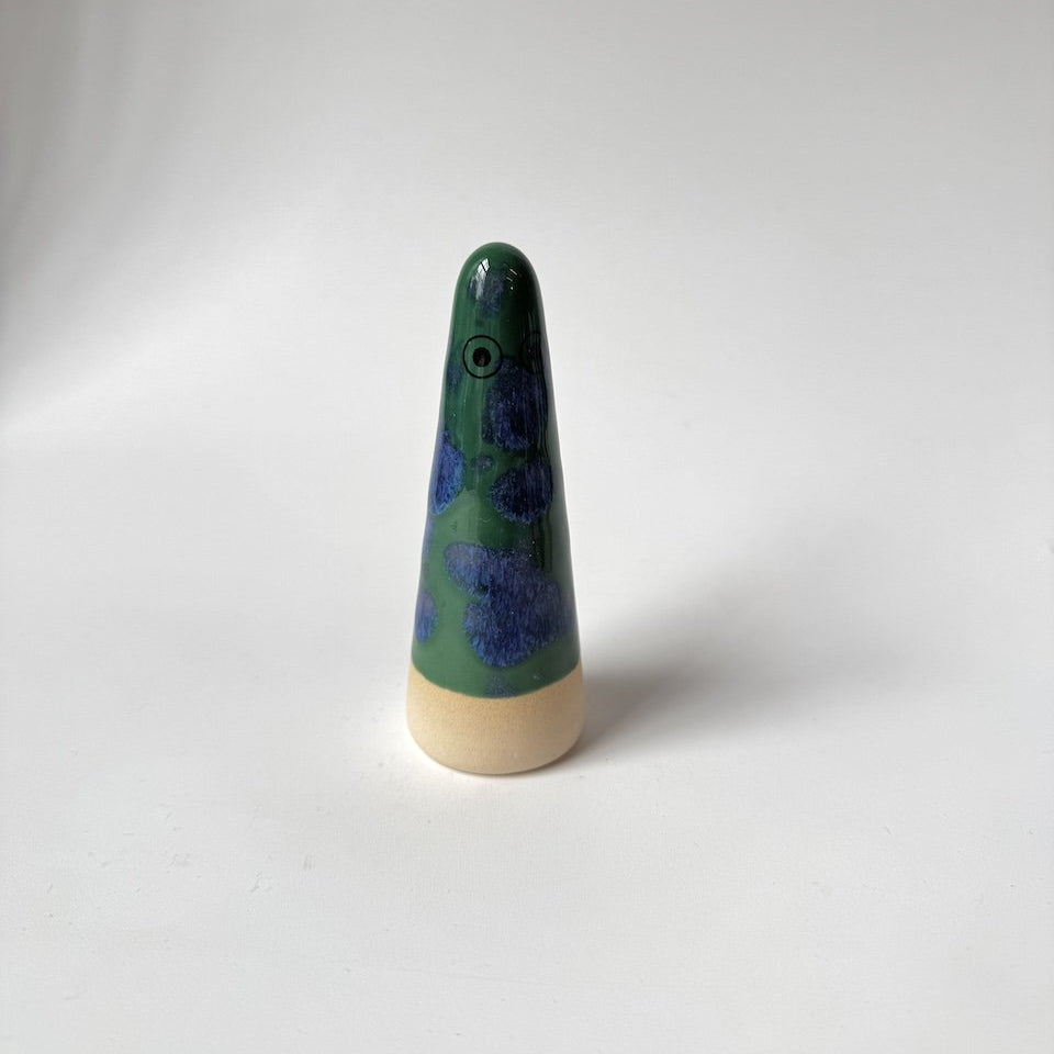 Levi Studio Arhoj ghost with a green and blue speckled body and a natural beige wooden base, standing on a white studio background.