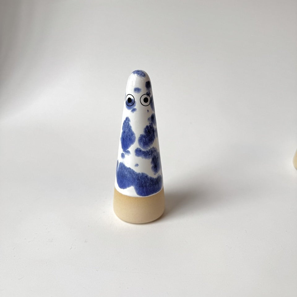 Alec Studio Arhoj ghost with a blue and white marbled pattern and eyes, standing on a beige base against a plain light gray background.