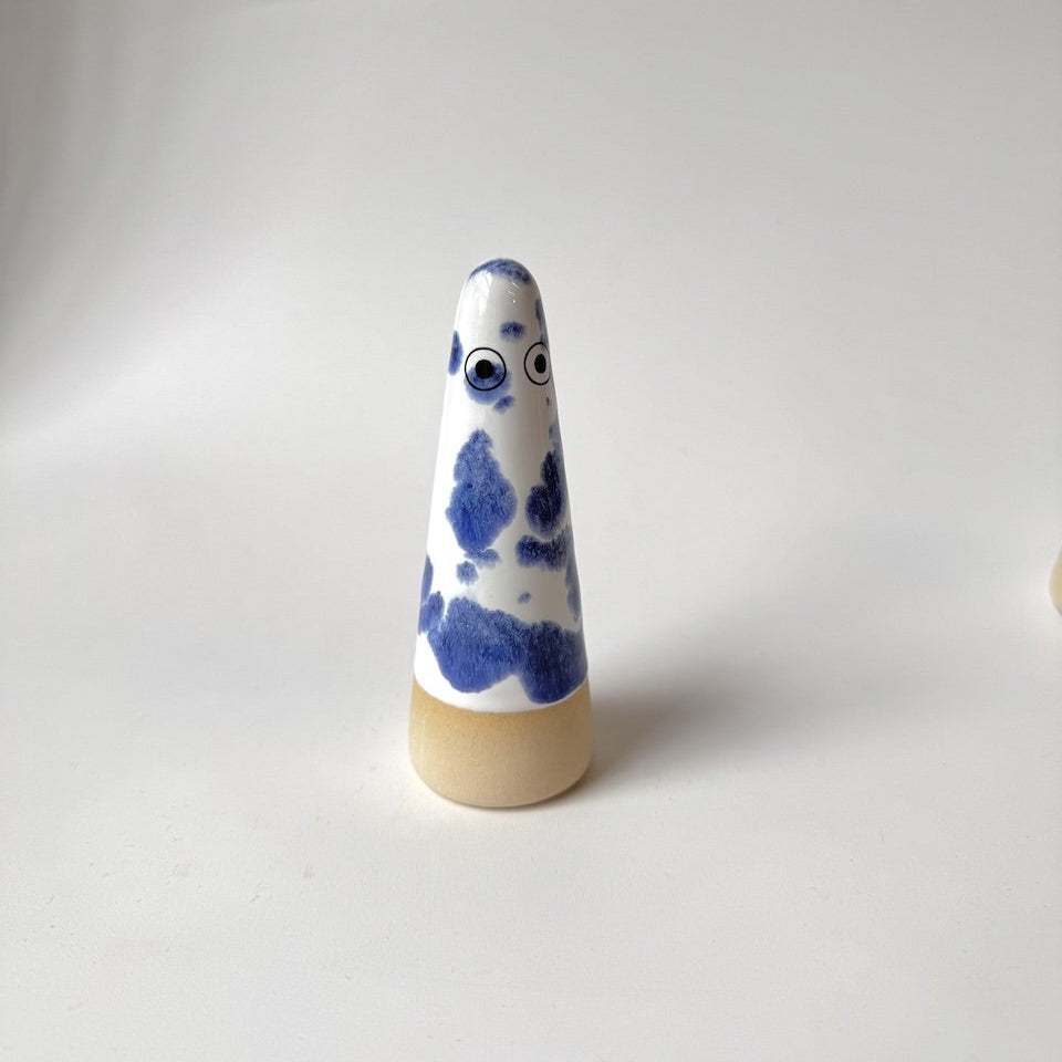 Alec Studio Arhoj ghost with a blue and white marbled pattern and eyes, standing on a beige base against a plain light gray background.