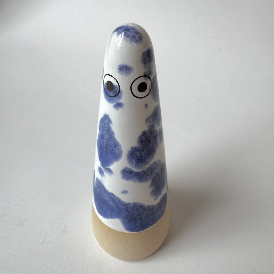 Alec Studio Arhoj ghost with a blue and white marbled pattern and eyes, standing on a beige base against a plain light gray background.