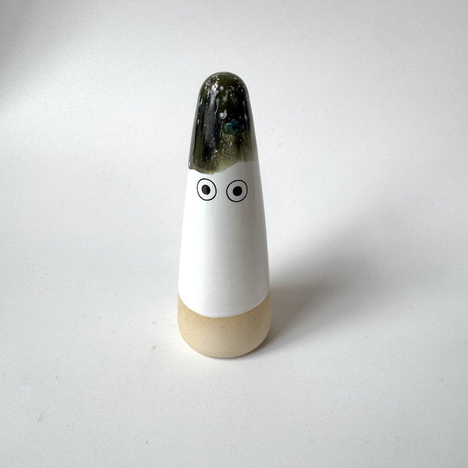 Sed Studio Arhoj ghost with a glossy dark green glazed top, a white middle section with two simple black eyes, and a light beige base, set against a plain light grey background.
