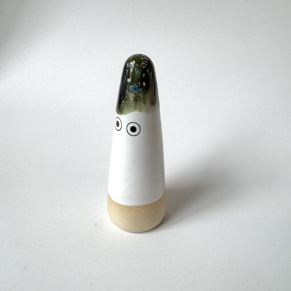 Sed Studio Arhoj ghost with a glossy dark green glazed top, a white middle section with two simple black eyes, and a light beige base, set against a plain light grey background.