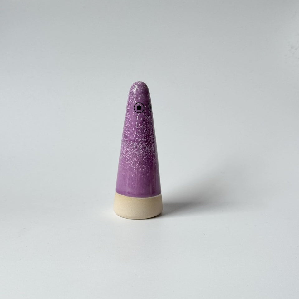 Odette Studio Arhoj ghost with a purple speckled body and a beige base, featuring simple black eyes, set against a plain light grey background.