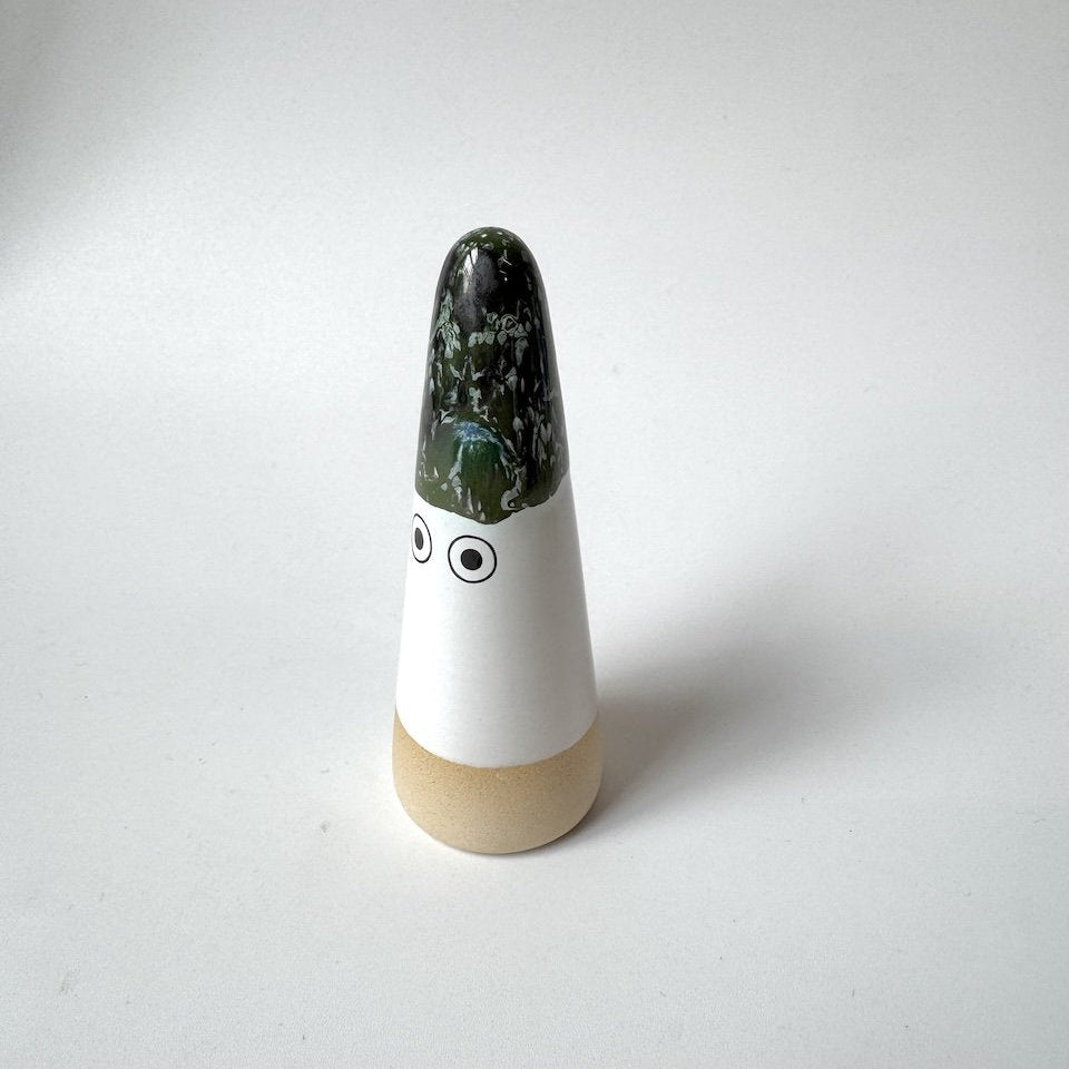 Sed Studio Arhoj ghost with a glossy dark green glazed top, a white middle section with two simple black eyes, and a light beige base, set against a plain light grey background.