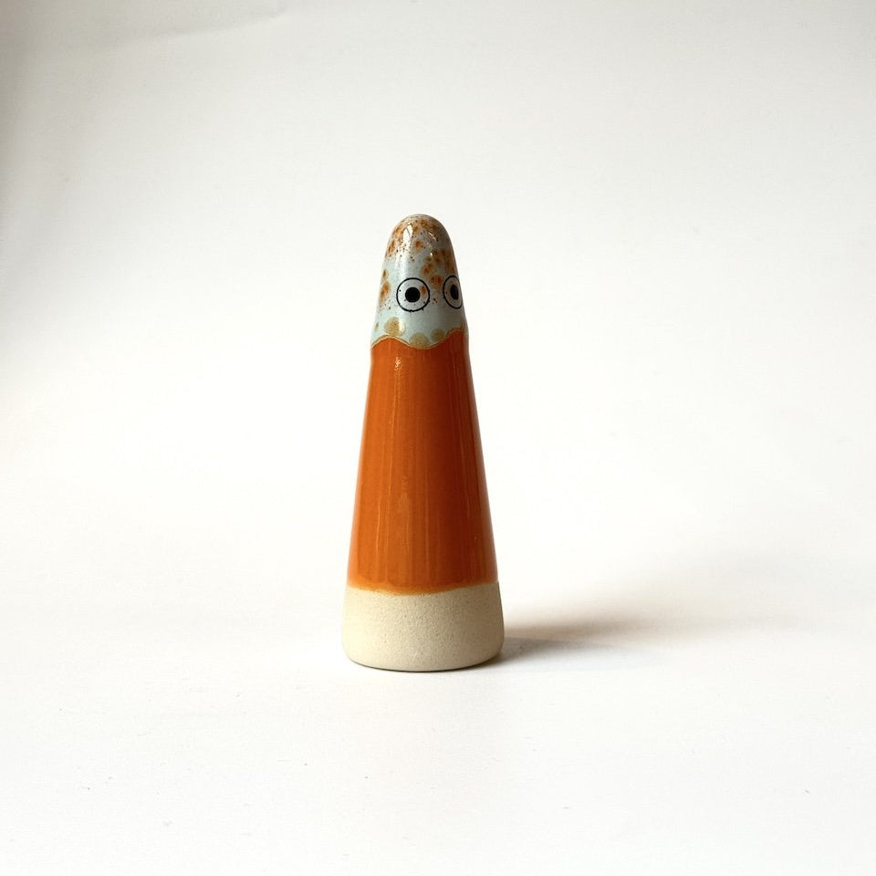 Freyja Studio Arhoj ghost, featuring an orange body, a cream-colored base, and a face with large black eyes and a patterned beige top.