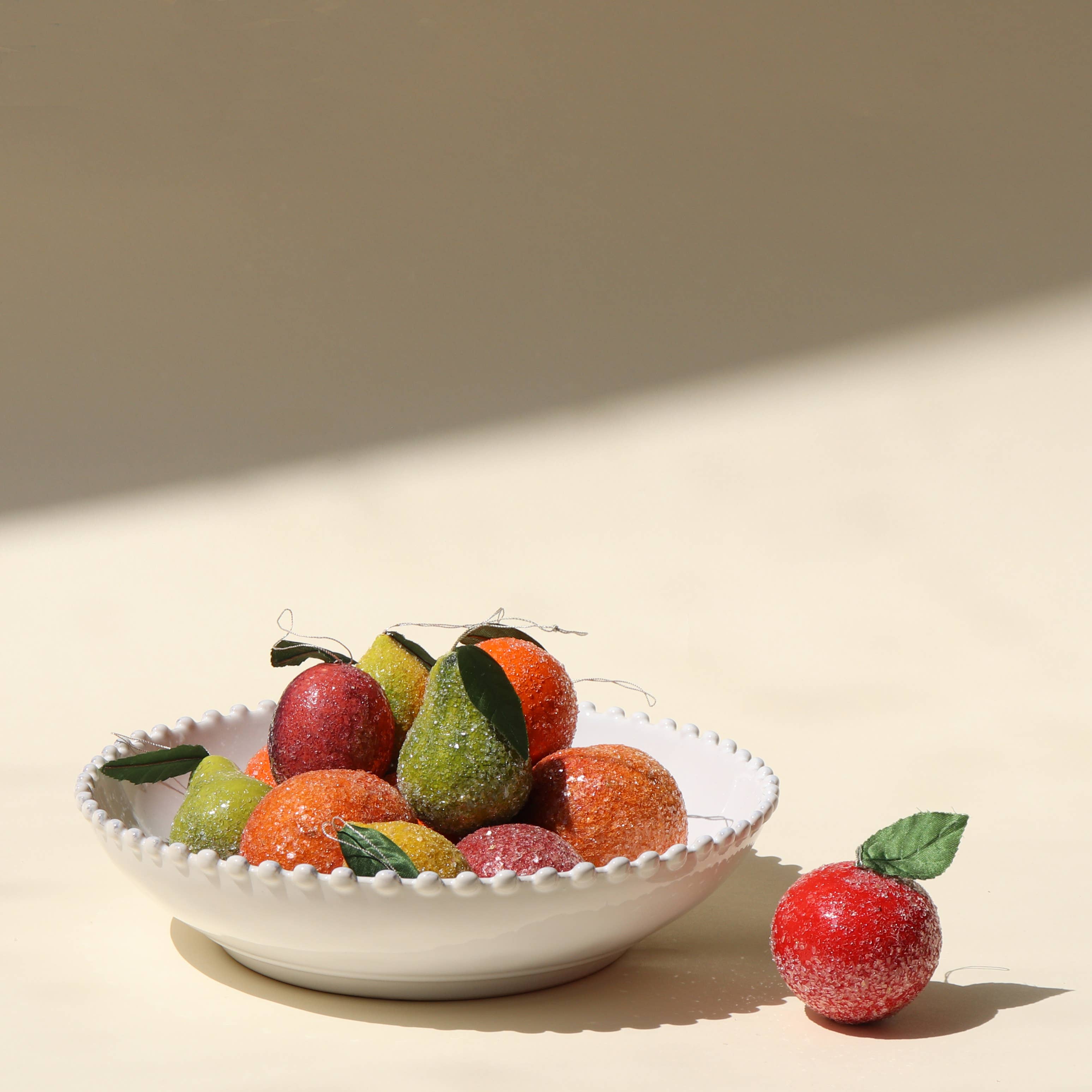 Decorative bowl with frosted ornamental fruit on a beige background