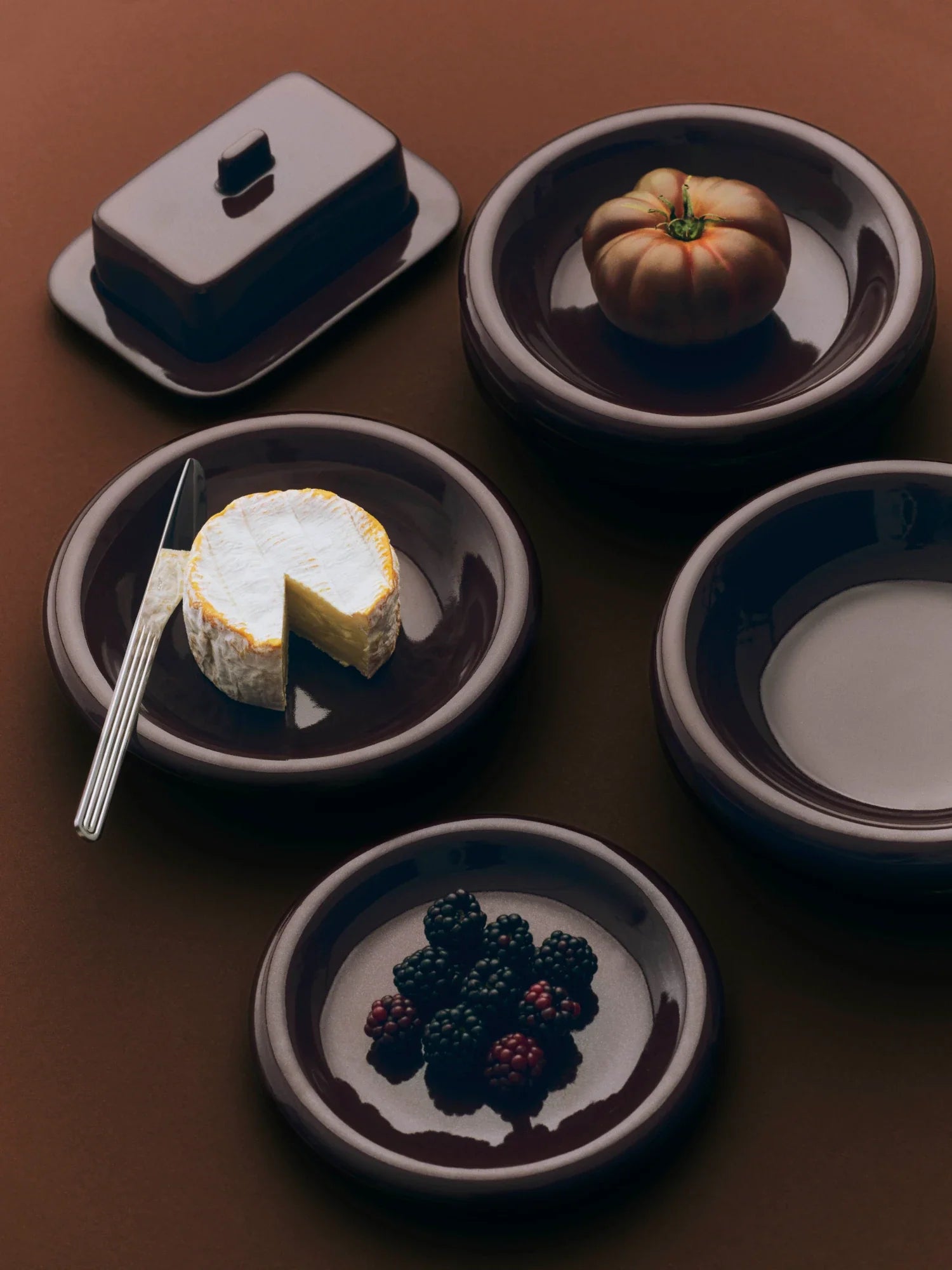 A selection of HAY patterned dinner candles stand in individual coloured holders on a square table