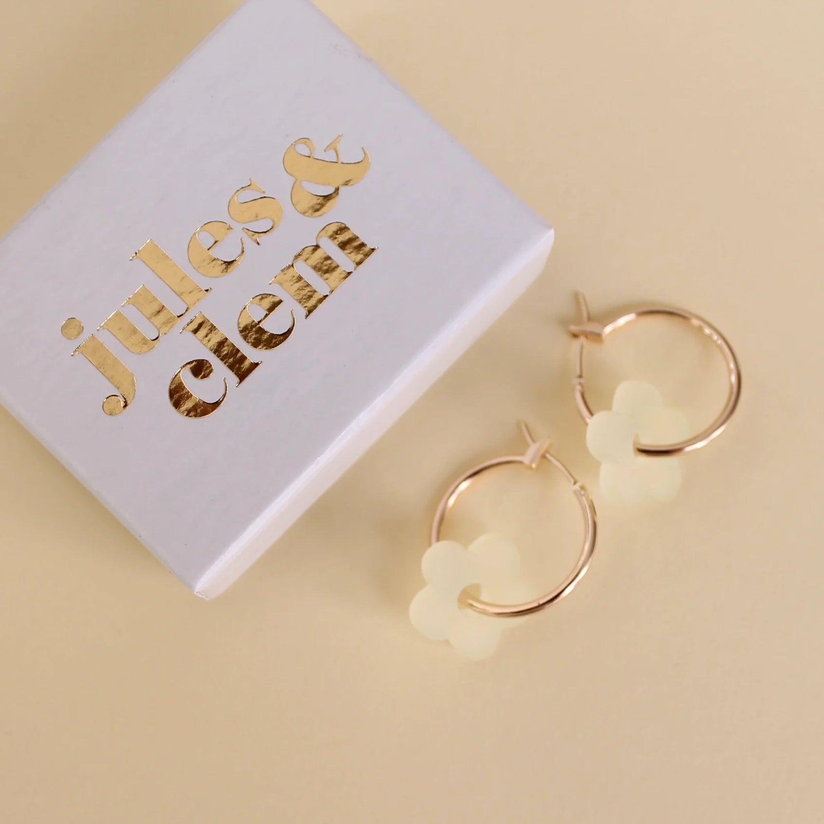 A pair of dark green and a pair of olive green scallop edged acrylic hoop earrings on a pale green background