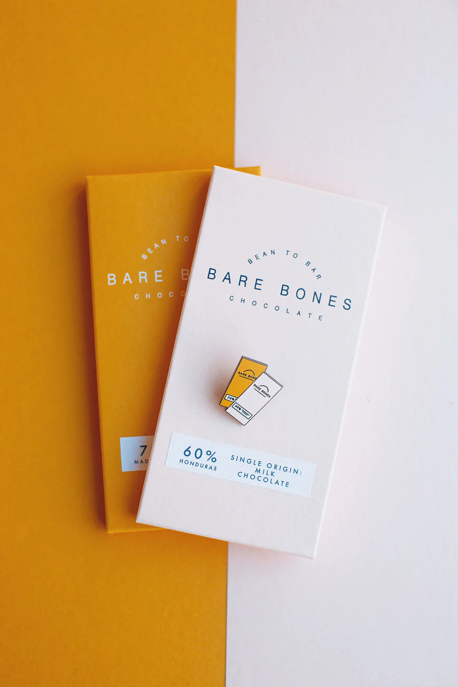 Bare Bones Chocolate packaging on a yellow and white background with the small Bar Bones badge of the same image on top