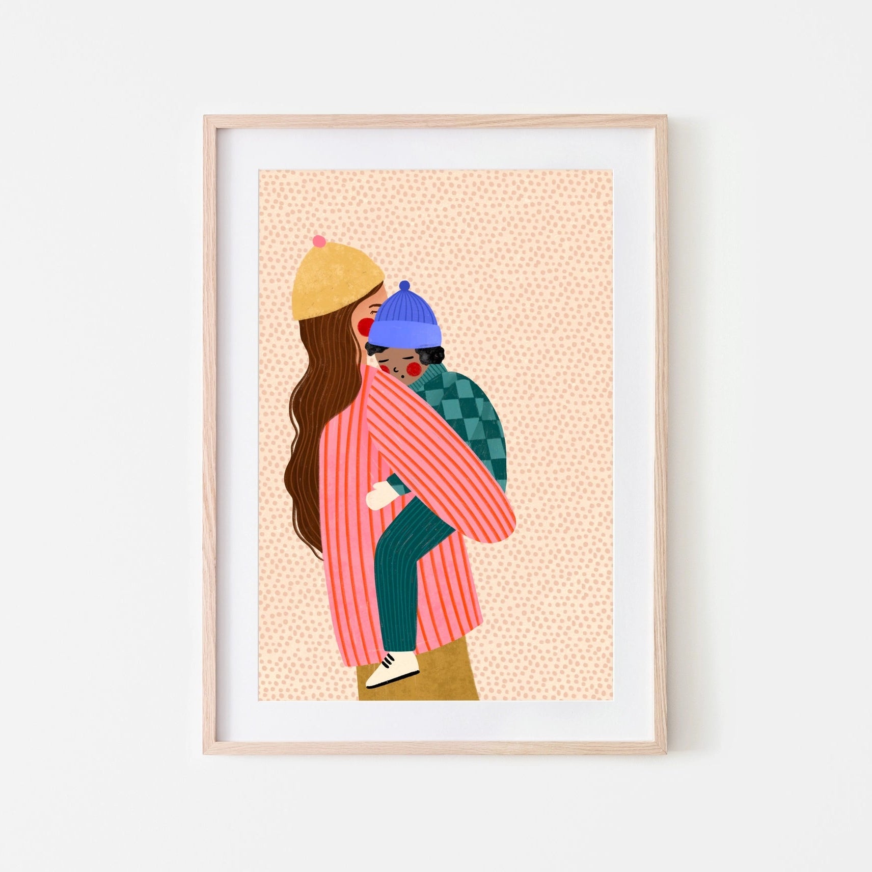 Framed artwork of a woman in pink hugging a child in blue and green on a peach background