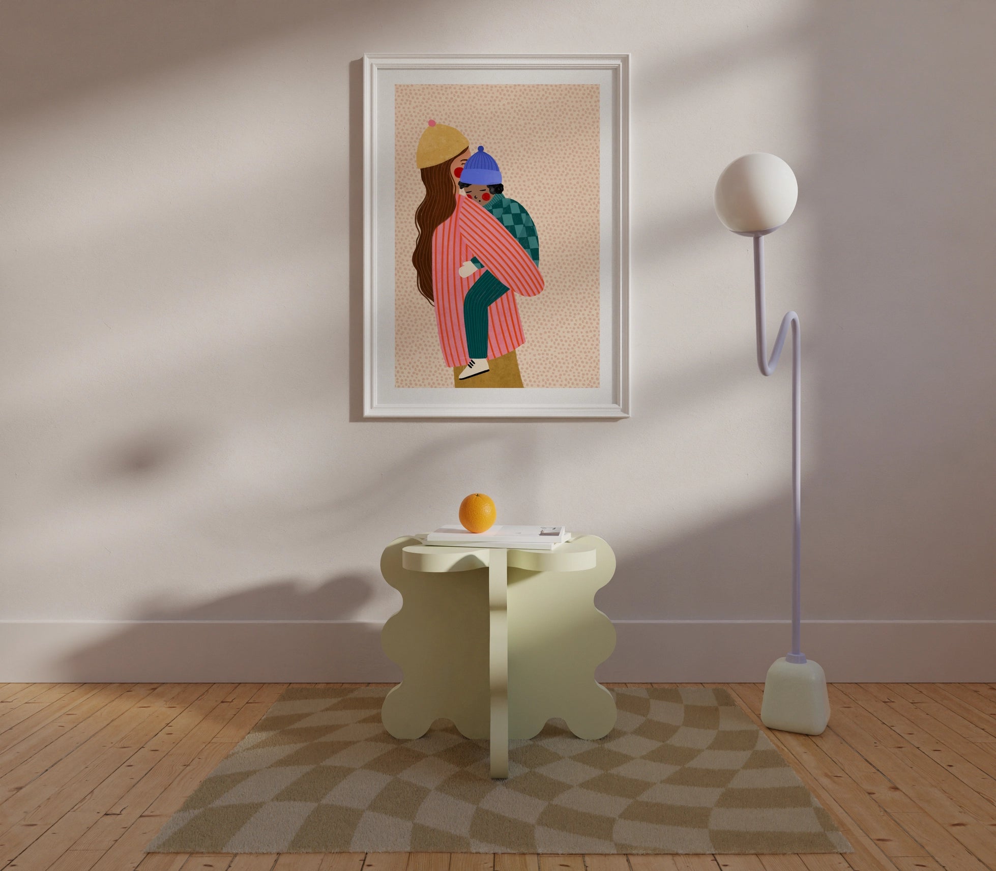 Framed artwork of two people embracing on a wall in a room with a side table and lamp.