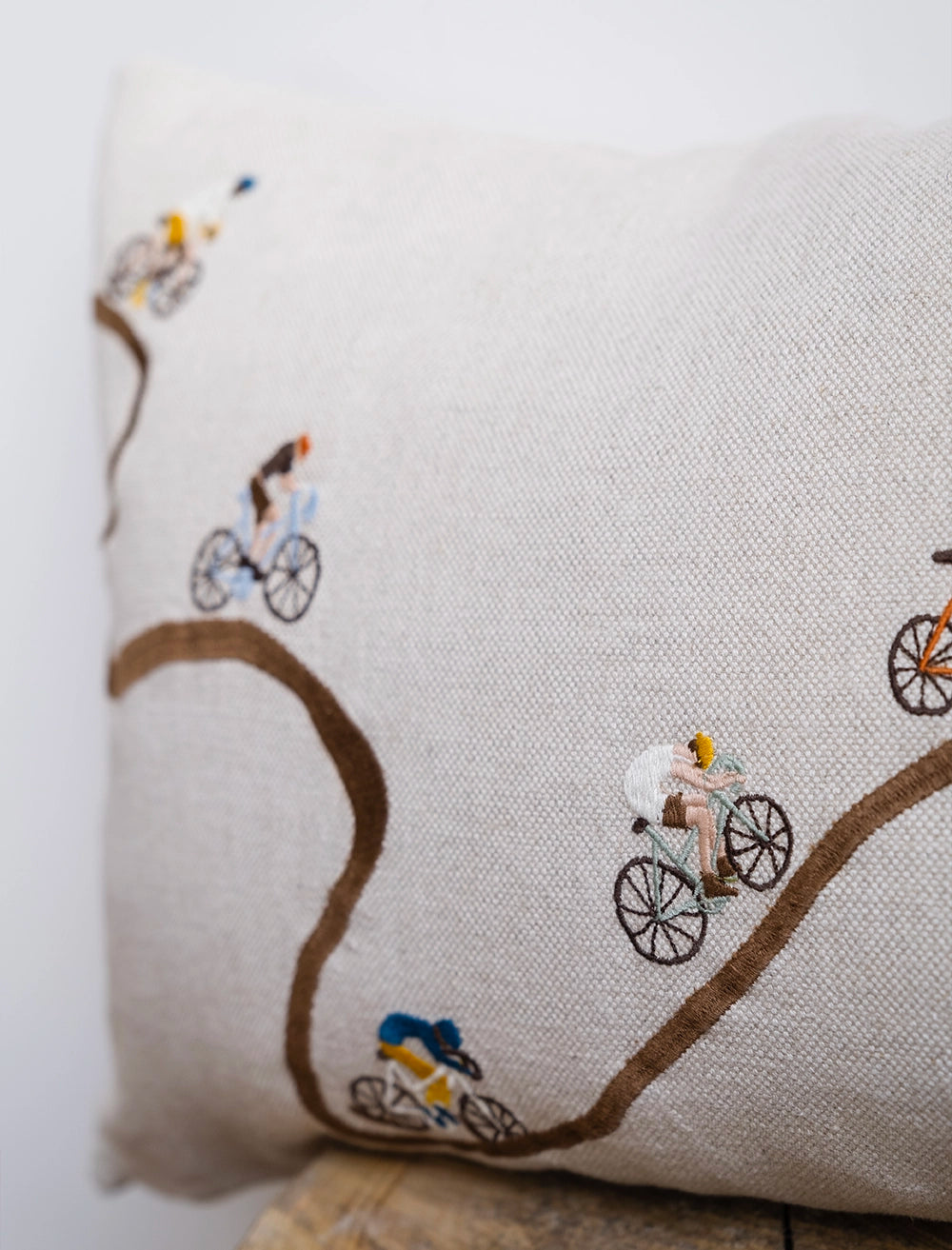 Close up details of embroidered cyclists on a natural linen cushion from Fine Little Day
